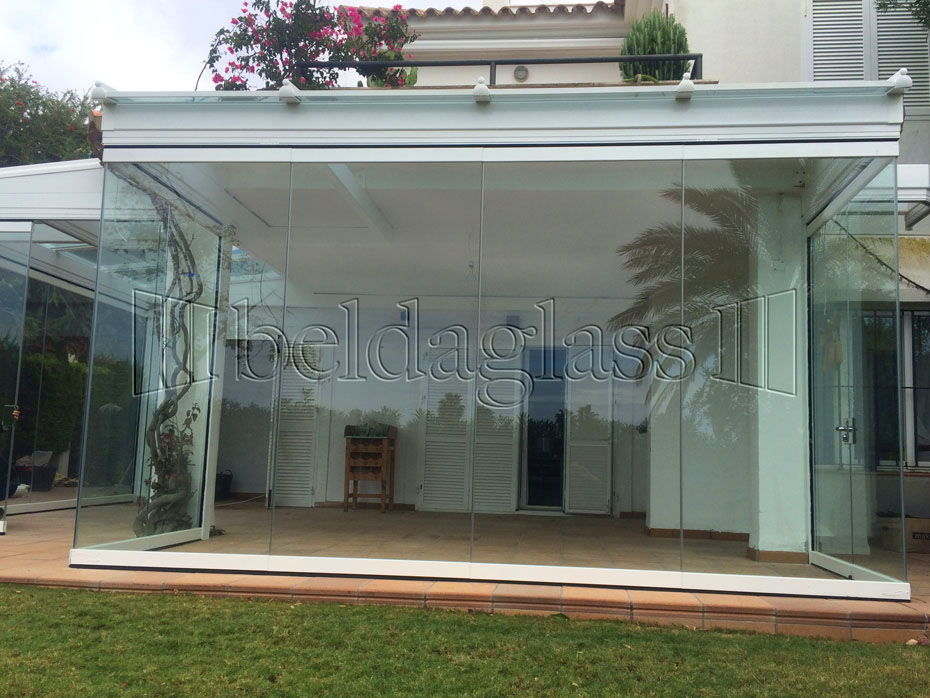 Proyecto de instalación de un porche acristalado en una vivienda en Rota, Cádiz, con techo de cristal y cortinas de cristal sin guía al suelo. ¡Llámanos!