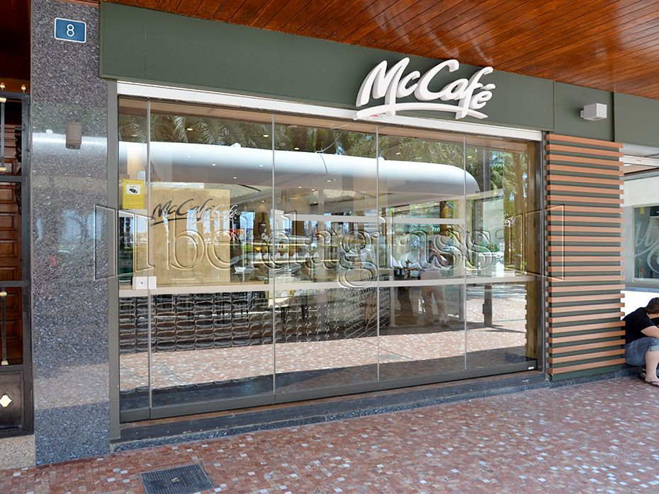 Beldaglass Integra su sistema de cortinas de cristal sin guía en el suelo en un McCafé de Alicante, preservando la imagen de marca y aprovechando el espacio