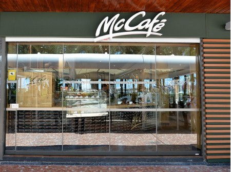 Beldaglass Integra su sistema de cortinas de cristal sin guía en el suelo en un McCafé de Alicante, preservando la imagen de marca y aprovechando el espacio